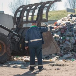 landfill-worker-directing-skid-steer-loader-waste-heap-rear-view_979187-4683